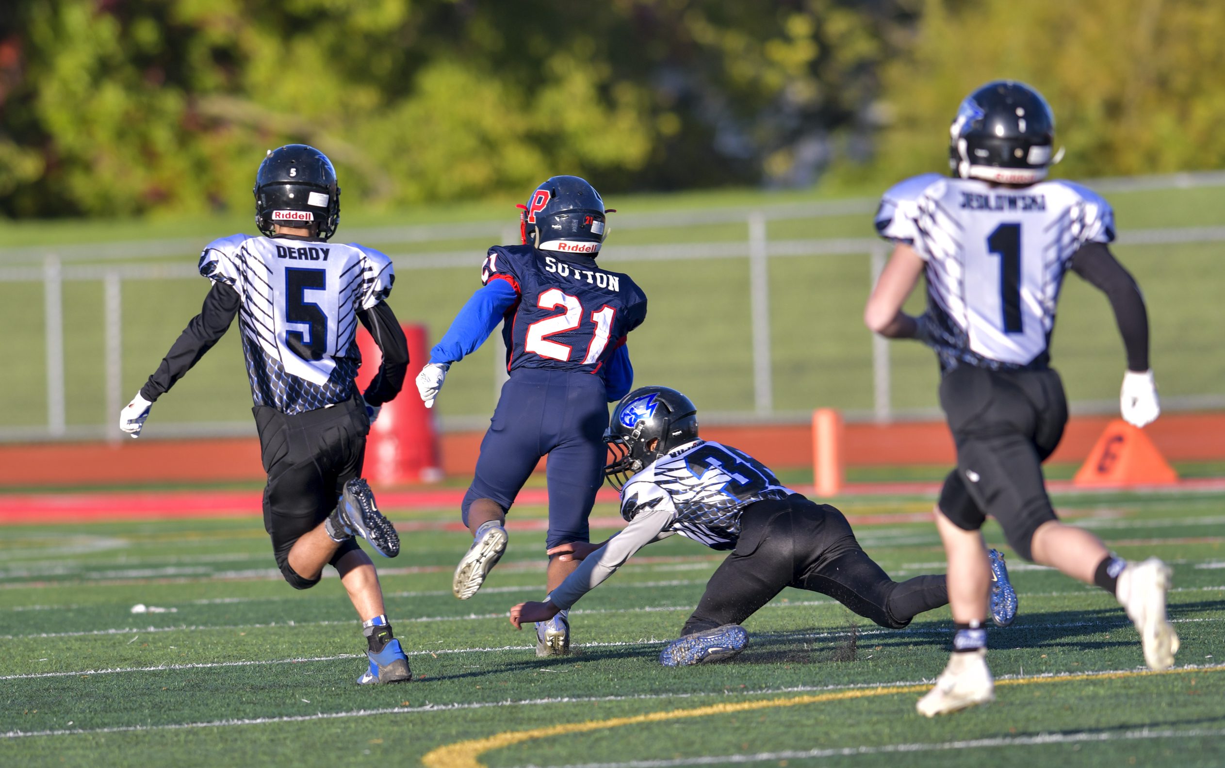 American football players running down field during game.